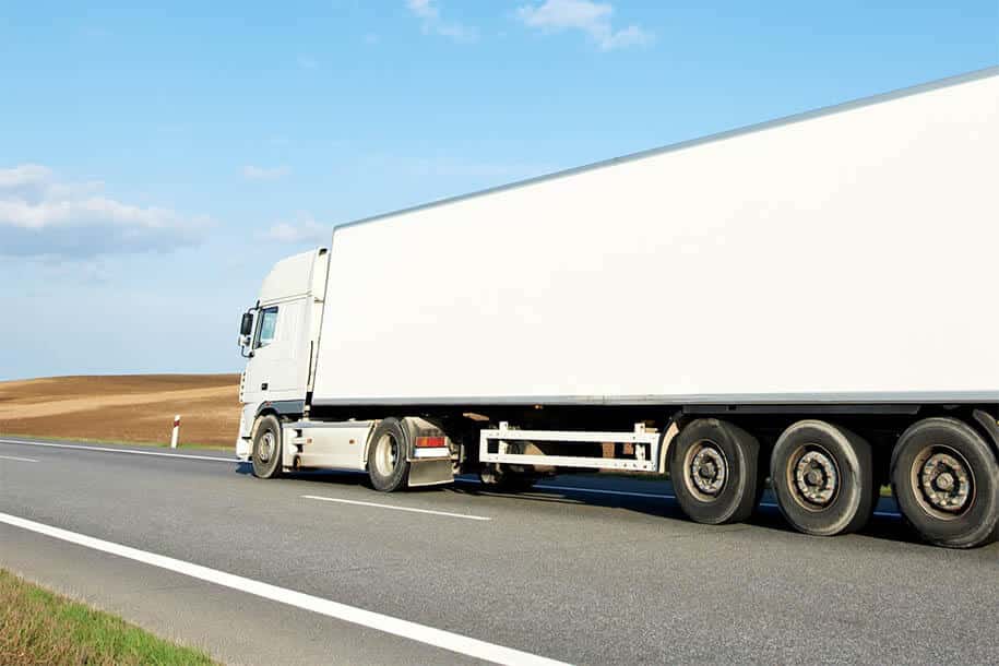 Lkw fährt auf einer Landstraße. - Leistungen - Komet Umzüge